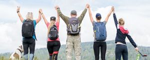 Grupo de pessoas comemorando após subir uma montanha.